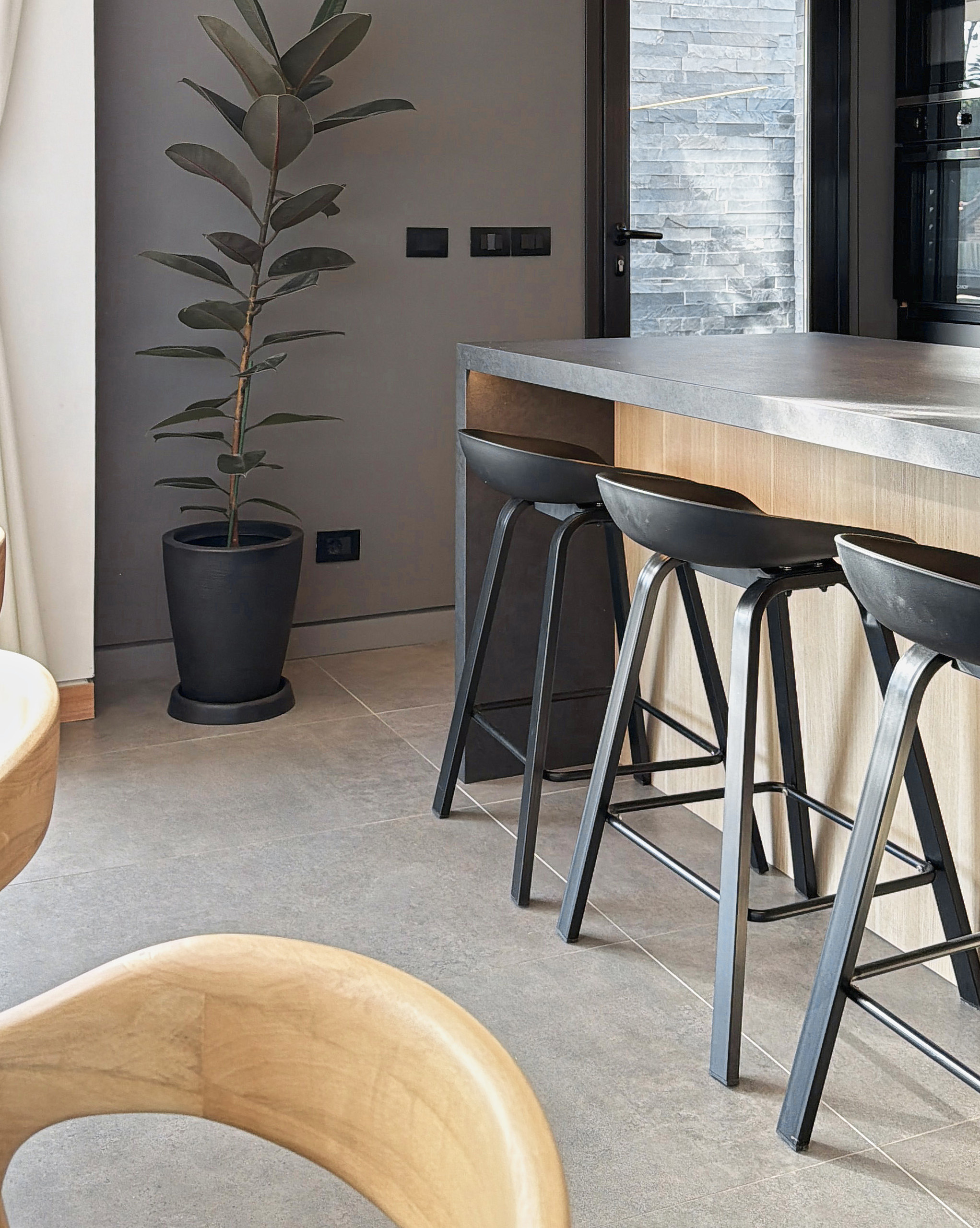 Detalle de la isla de cocina de Casa 9 Greenland con madera clara y banquetas negras